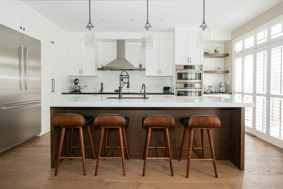 Modern white kitchen with island, barstools, and natural light — prepared and staged for sale