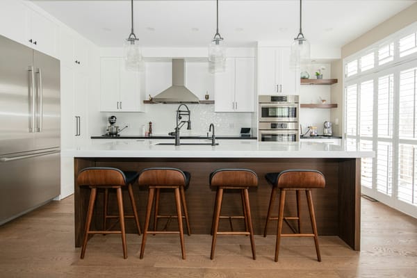 Modern white kitchen with island, barstools, and natural light — prepared and staged for sale